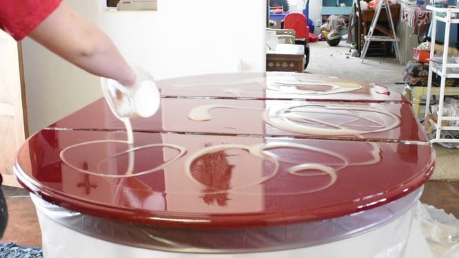 Lighter epoxy colors being added in swirling pattern to red-tinted epoxy layer.
